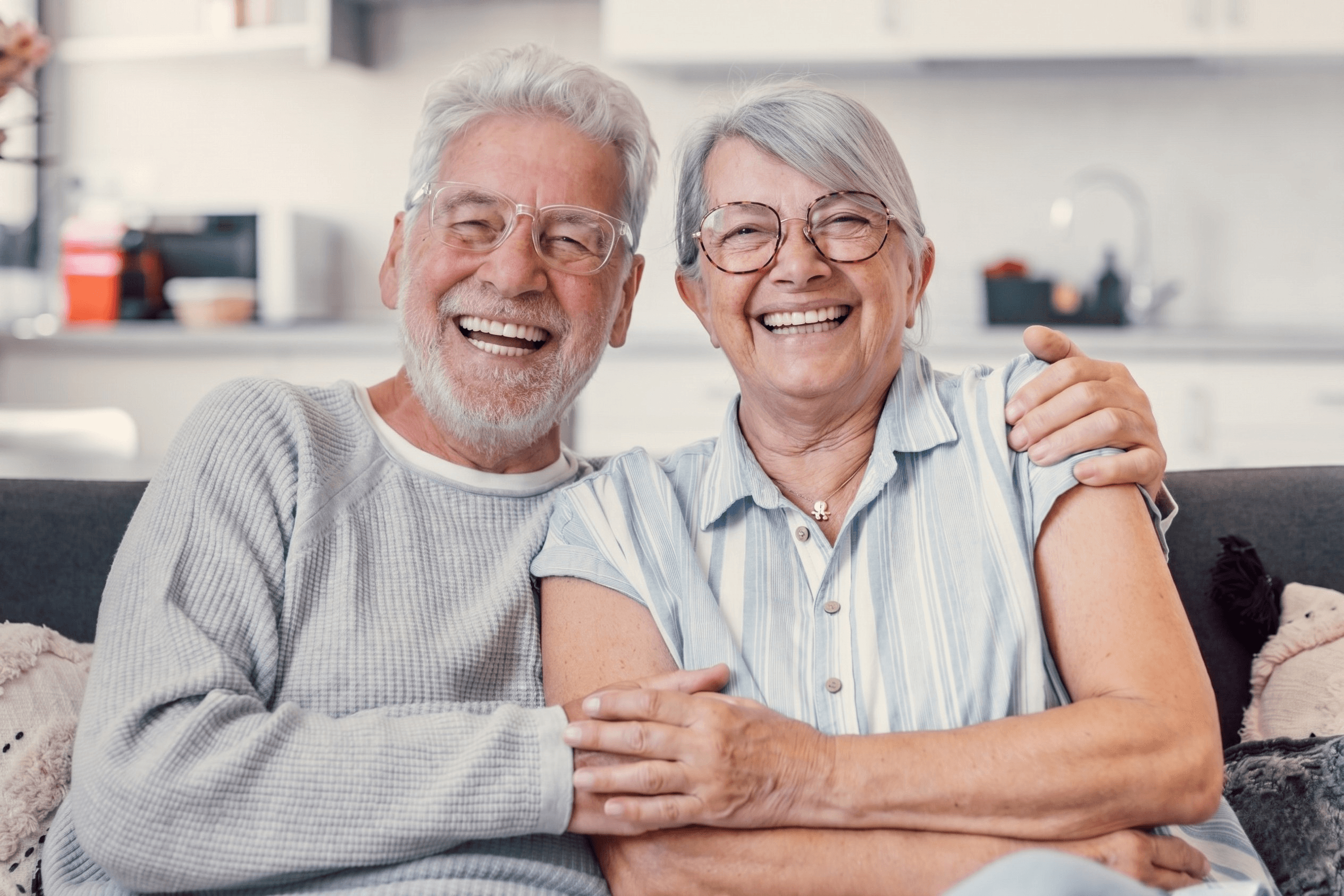 A happy older couple relaxing together on the sofa at home, laughing